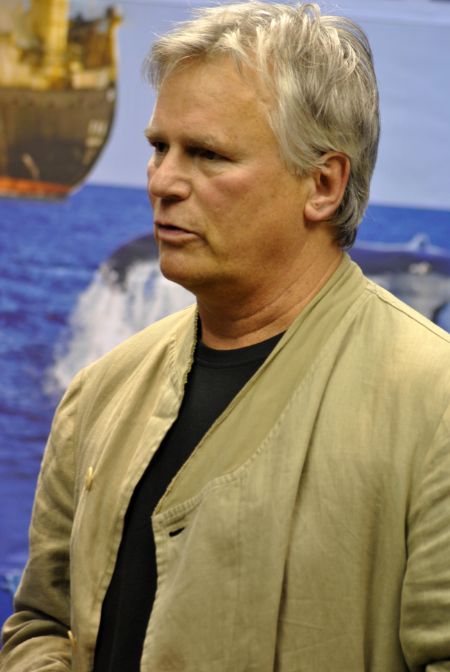 Richard Dean Anderson in a brown jacket poses for a picture.